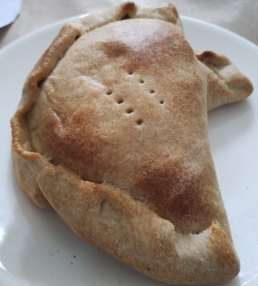Empanada al horno dorada servida en plato blanco
